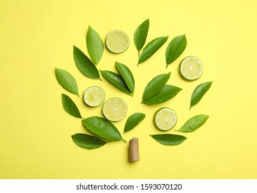 Flat lay composition with fresh green citrus leaves and lime slices on yellow background