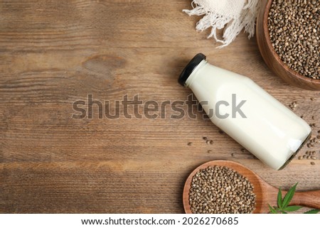 Flat lay composition with fresh hemp milk on wooden table. Space for text