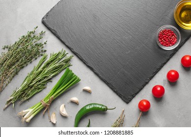 Flat lay composition with fresh herbs and slate plate on grey background