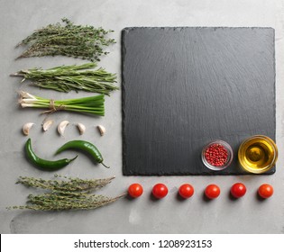 Flat lay composition with fresh herbs and slate plate on grey background