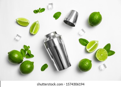 Flat lay composition with fresh juicy limes, mint, ice cubes and cocktail shaker on white background