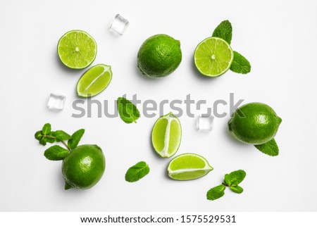 Flat lay composition with fresh juicy limes, mint and ice cubes on white background