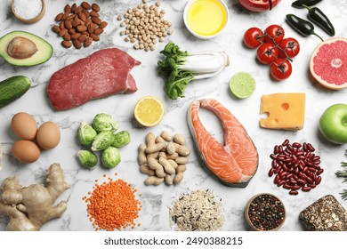 Flat lay composition with fresh meat and other products for balanced diet on white marble table