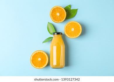 Flat lay composition with fresh orange juice in bottle and oranges with leaves on color background, space for text. Fresh natural drink