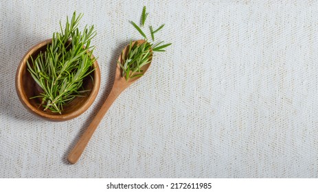 Flat Lay Composition With Fresh Rosemary In Wooden Bowl And Spoon On Beige Linen Table Cloth. Top View. Copy Space For Your Text.