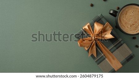 Flat lay composition of a gift box tied with a gold ribbon and a cup of coffee on a green surface, creating a cozy and festive scene suitable for celebrations or special occasions
