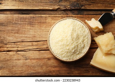 Flat lay composition with grated parmesan cheese and knife on wooden table. Space for text