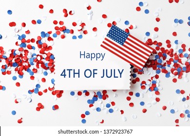 Flat lay composition with greeting card, USA flag and confetti on white background. Happy Independence Day