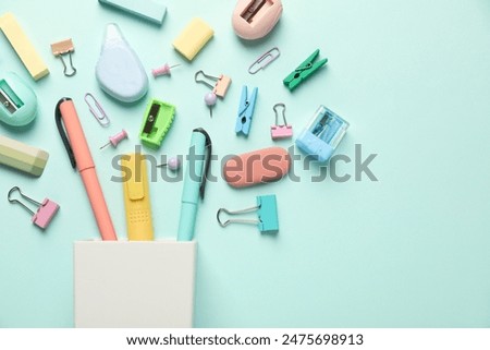 Flat lay composition with holder and different stationery on turquoise background, space for text