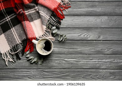 Flat lay composition with hot drink and warm plaid on black wooden table, space for text