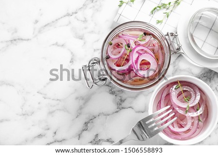 Flat lay composition with jar of pickled onions on marble table. Space for text