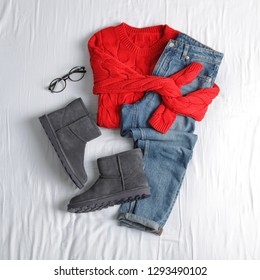 Flat lay composition with jeans, sweater and shoes on white fabric