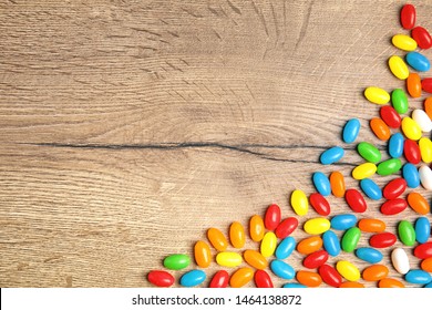 Flat lay composition with jelly beans on wooden background. Space for text