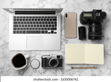 Flat lay composition with laptop, cameras and smartphone on white marble table. Designer's workplace - Powered by Shutterstock