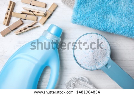 Flat lay composition with laundry detergents, clothespins and towels on white wooden background