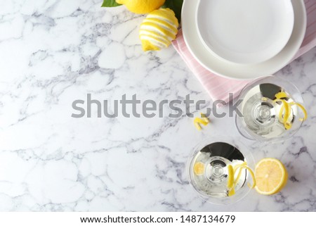 Flat lay composition of lemon drop martini cocktails with zest on white marble table. Space for text