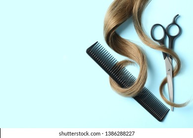 Flat lay composition with light brown hair, comb, scissors and space for text on color background. Hairdresser service