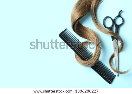 Flat lay composition with light brown hair, comb, scissors and space for text on color background. Hairdresser service