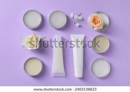 Flat lay composition with lip balms and flowers on lilac background