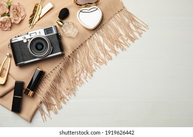 Flat lay composition with makeup products and camera on white wooden background. Space for text