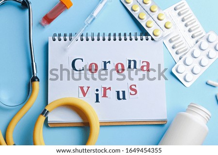 Flat lay composition of medications and notebook with words CORONA VIRUS on light blue background