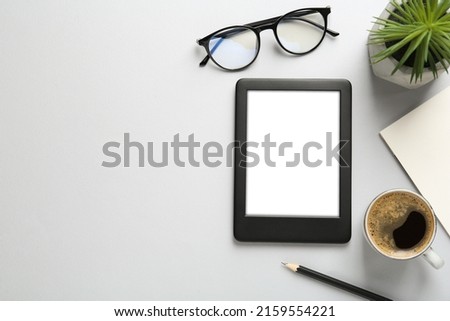 Flat lay composition with modern e-book reader on white background, space for text