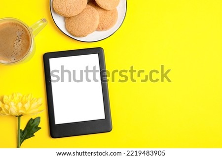 Flat lay composition with modern e-book reader on yellow background. Space for text