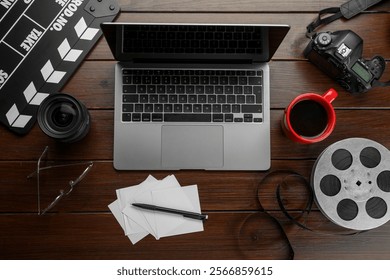 Flat lay composition with movie clapper, film reel, camera and laptop on wooden table