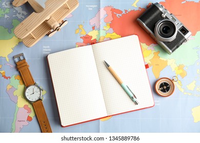 Flat lay composition with notebook and camera on world map, space for text. Travel agency