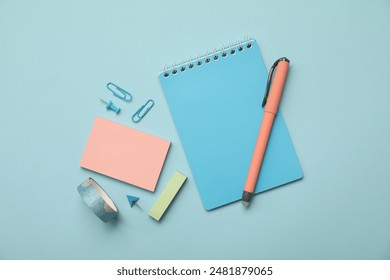 Flat lay composition with notebook and different stationery on light blue background