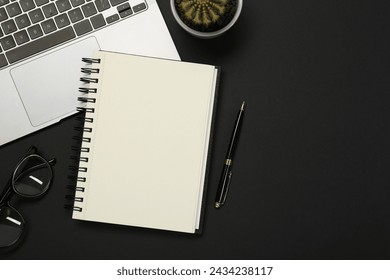 Flat lay composition with notebook and laptop on black table. Space for text