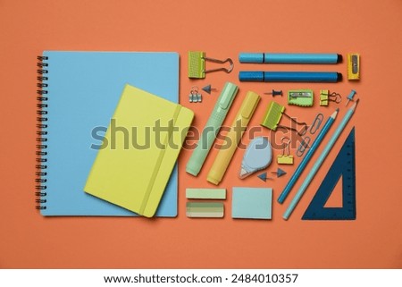 Flat lay composition with notebooks and different stationery on orange background