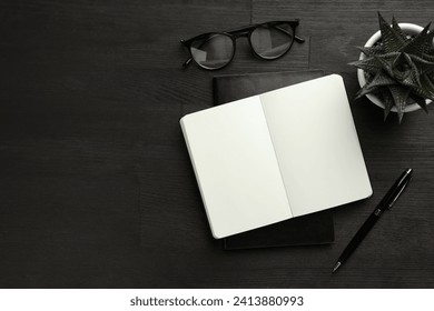 Flat lay composition with notebooks and pen on black wooden table. Space for text