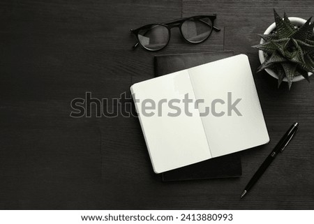 Flat lay composition with notebooks and pen on black wooden table. Space for text
