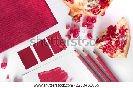 flat lay composition on white backgrond, fabric, pens, and pomegranate viva magenta color