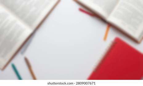 Flat lay composition of open books, a red notebook, and colored pencils arranged on a clean white surface, suggesting study or creativity.