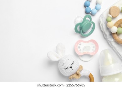 Flat lay composition with pacifiers and other baby stuff on white background. Space for text