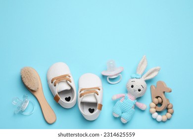 Flat lay composition with pacifiers and other baby stuff on light blue background. Space for text