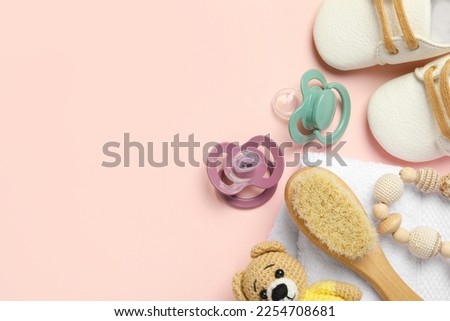 Flat lay composition with pacifiers and other baby stuff on pink background. Space for text