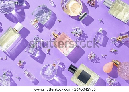Flat lay composition with perfume bottles and lilac flowers on violet background