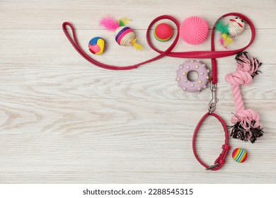 Flat lay composition with pet leash and toys on white wooden background, space for text