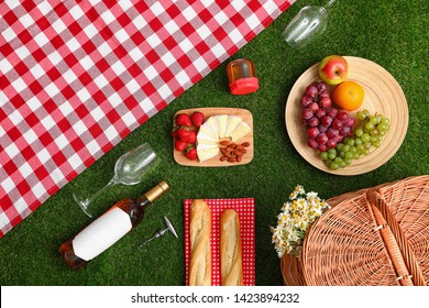 Flat lay composition with picnic blanket, products and wine on grass