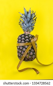 Flat lay composition with pineapple, measuring tape on vibrant yellow background.
