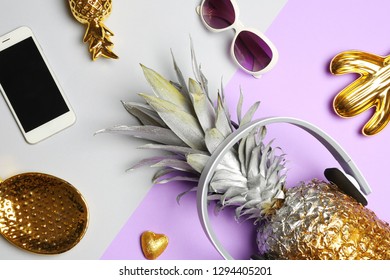 Flat lay composition with pineapple, smartphone, sunglasses and headphones on color background