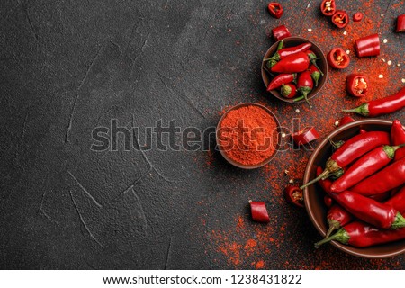 Flat lay composition with powdered and raw chili peppers on dark background. Space for text