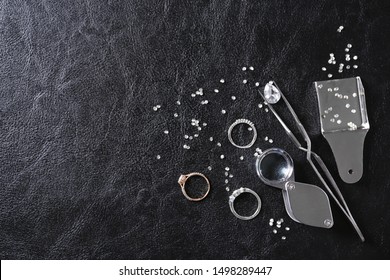 Flat lay composition with precious stones and jewelry tools on black leather background, space for text