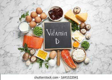 Flat lay composition with products rich in vitamin D on white marble table
