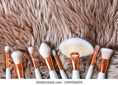Flat lay composition of professional makeup brushes on furry fabric. Space for text