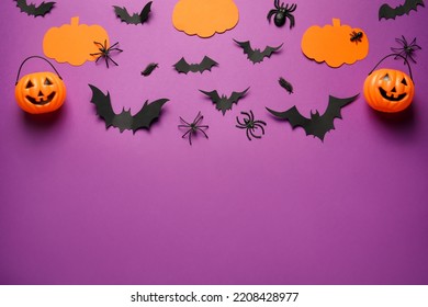 Flat lay composition with pumpkins, spiders and paper bats on purple background, space for text. Halloween celebration