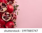 Flat lay composition with ripe pomegranates on pink background. Space for text
